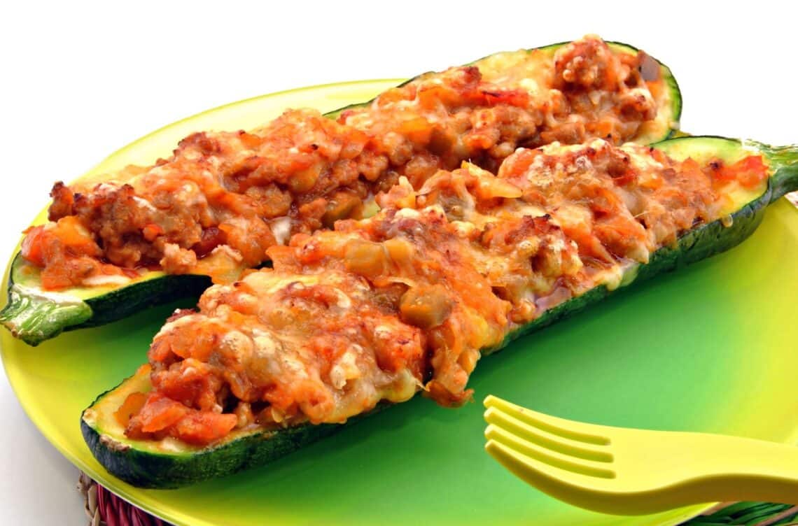 Two Turkey-Stuffed Zucchini Boat On A Green Plate