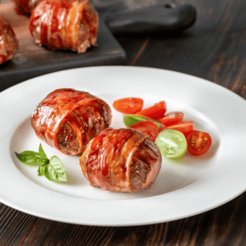 Easy Bacon Wrapped Paleo Meatballs 2 2 Bacon Wrapped Paleo Meatballs On A White Plate With Sliced Cherry Tomatoes