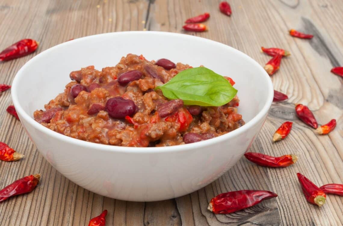 The Perfect Chili Recipe In A White Bowl With Chilis Around