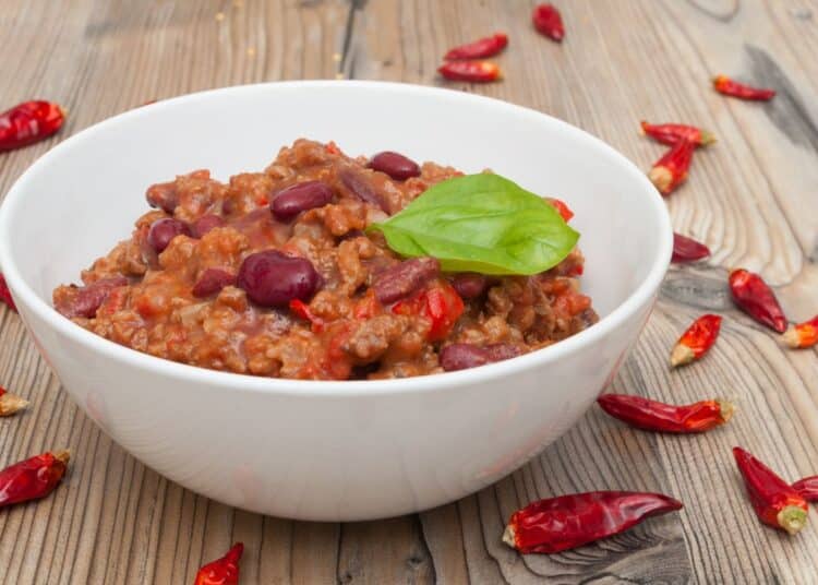 The Perfect Chili Recipe In A White Bowl With Chilis Around