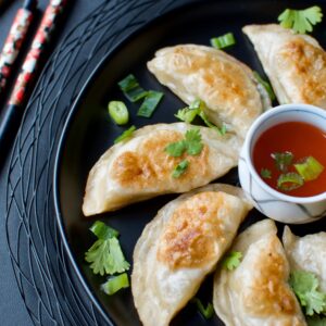 Ginger Pork Pot Stickers Served With Sauce And Chopsticks