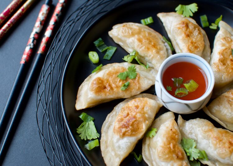 Ginger Pork Pot Stickers Served With Sauce And Chopsticks